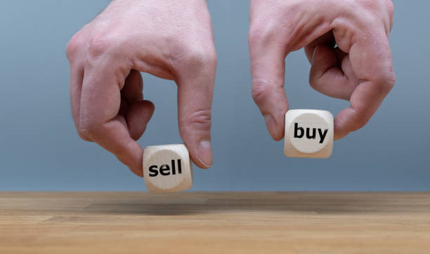 Hands are holding two cubes with the words "sell" and "buy". One hand rises the cube with the word "buy". stock photo