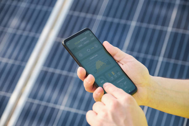 Hands checking solar power generation in a smartphone app. stock photo