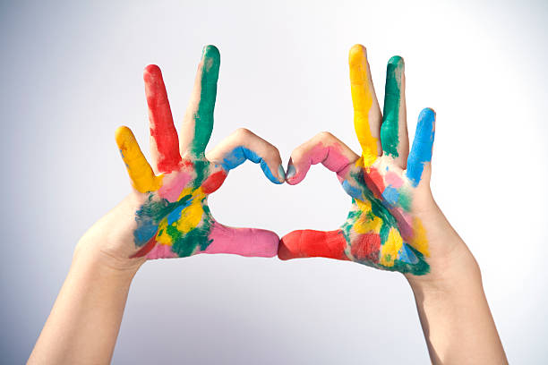 Hands covered in paint making a heart sign stock photo