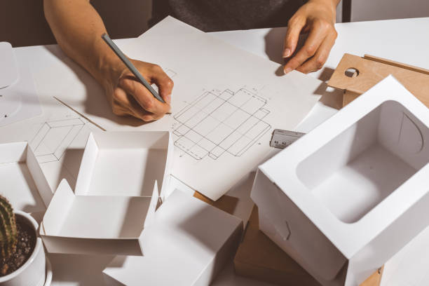 Hands designer draws a sketch of paper packaging. Creative development of ecological boxes. stock photo