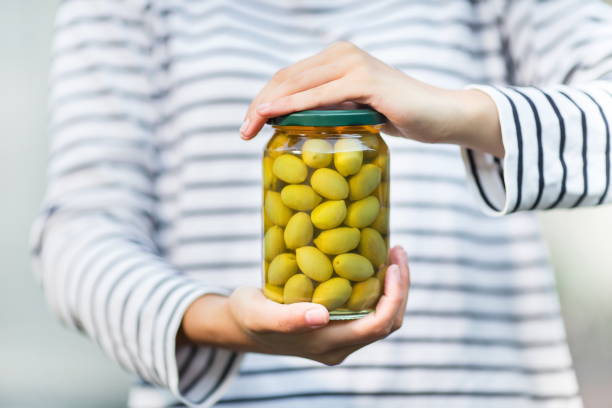 hands hold a can of marinated olives hands hold a can of marinated olives green olives jar stock pictures, royalty-free photos & images