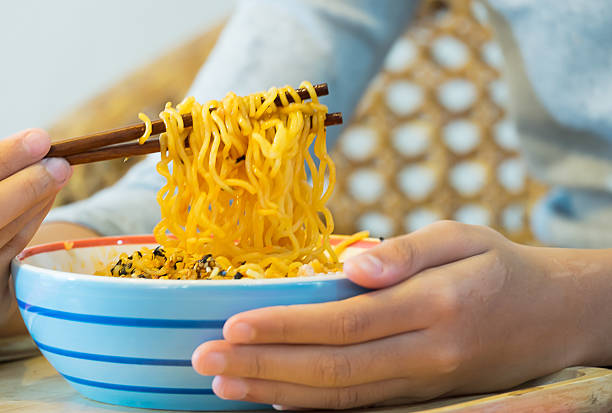 Hands hold Noodles Bowl and Use Chopstick to  fork over stock photo