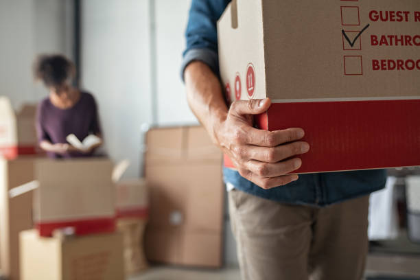 Hands holding cardboard box during relocation Closeup of man hand holding cardboard at new home. Young man unpacking boxes in new apartment. Man hand carrying carton box while relocating with his girlfriend. relocation photos stock pictures, royalty-free photos & images
