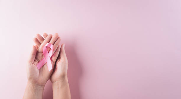 Hands holding pink ribbon, Breast cancer awareness, symbolic bow color raising awareness on women's breast tumor. Healthcare and medical concept. stock photo