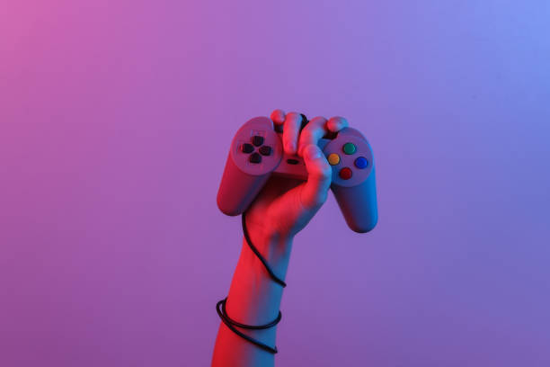 Hands holding retro joystick in blue-red neon gradient light. Old gaming. 80s retro wave. Minimalism stock photo