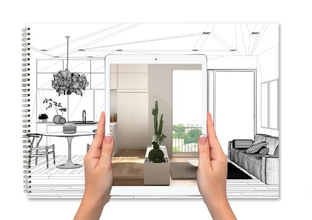 Hands holding tablet showing kitchen, notebook with blueprint sketch in the background, augmented reality concept, application to simulate furniture and interior design products stock photo