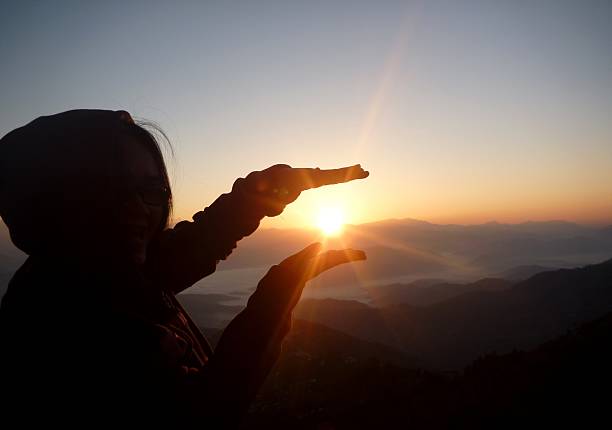 hands holding the sun at dawn stock photo