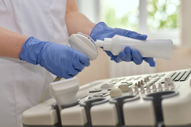 Hands in gloves apply a strip of transparent gel to the ultrasonic scanner sensor. The doctor in blue gloves applies a strip of transparent gel to the ultrasonic scanner sensor above the control panel. gel pack stock pictures, royalty-free photos & images