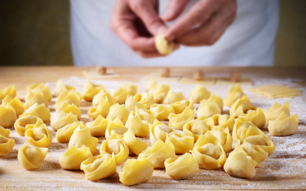 Hands make homemade tortellini, selective focus. Stuffed egg pasta, traditional Italian recipe. uncooked pasta stock pictures, royalty-free photos & images