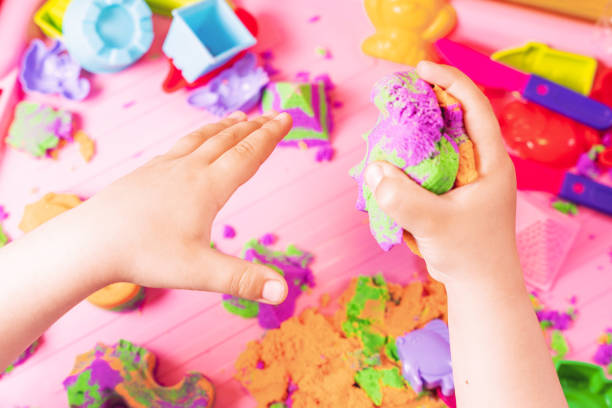 Hands of a child playing with multicolored kinetic sand stock photo
