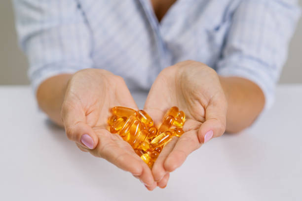 Hands of a woman holding fish oil Omega-3 capsules. Hands of a woman holding fish oil Omega-3 capsules. fish oil stock pictures, royalty-free photos & images
