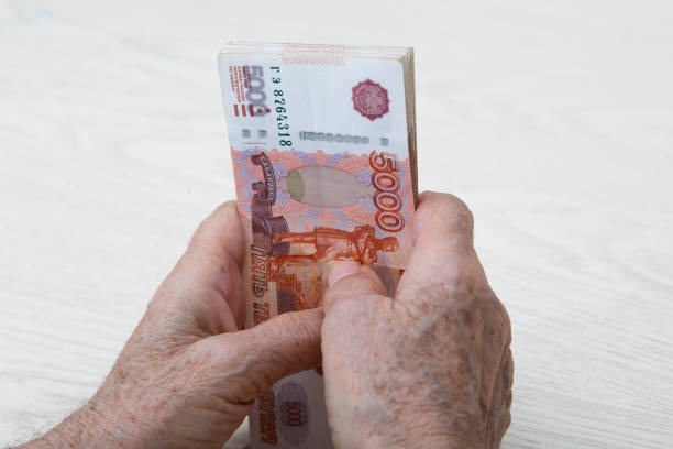 5000 루블로 표시된 러시아 돈 묶음으로 노인 여성의 손을 클로즈업. - 러시아 루블 뉴스 사진 이미지