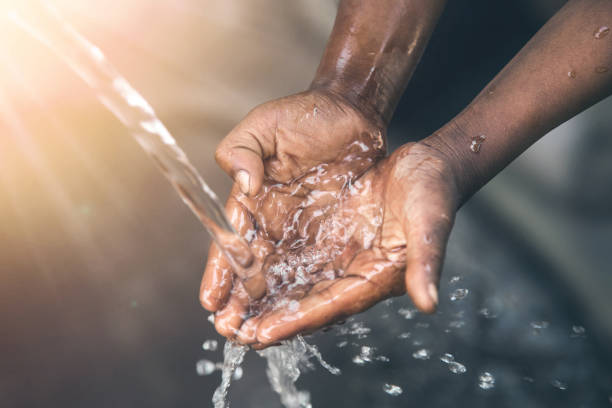 Hands of poor child - scoop drinking water, Africa The hands of a child from a poor community are outstretched to receive a flowing stream of clear, fresh water. developing countries stock pictures, royalty-free photos & images