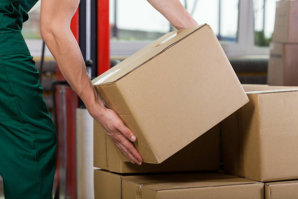 Hands of warehouse worker lifting box Hands of warehouse worker lifting box, horizontal picking up stock pictures, royalty-free photos & images