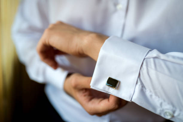 Hands of wedding groom buttoning up his white shirt. stock photo