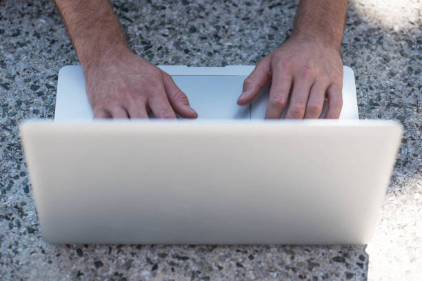 Hands on the laptop Close up photo of young male hands on the laptop on concrete surface. Shot made in Ljubljana, Slovenia, Europe in August 2017. Portable DVD Player stock pictures, royalty-free photos & images