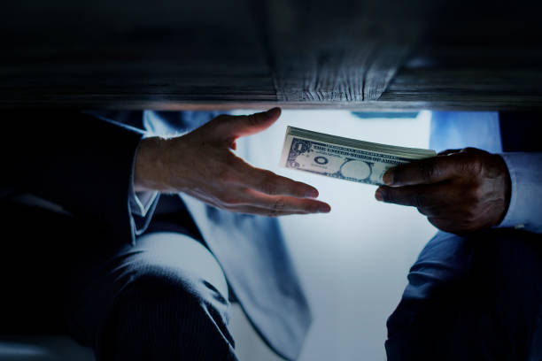 Hands passing money under table corruption bribery Hands passing money under table corruption bribery bribing stock pictures, royalty-free photos & images