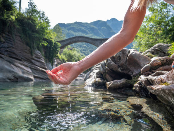 Hands scooping water from river Female hand cupped catching fresh water from mountain river in Switzerland detox body stock pictures, royalty-free photos & images
