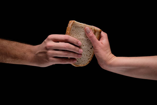 Hands sharing slice of bread Studio shot on the black background of man and woman hands holding together slice of  white bread rich strike stock pictures, royalty-free photos & images