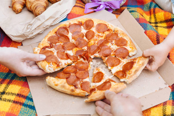 Hands take slices of pepperoni pizza, food delivery, picnic cheese hamper delivery stock pictures, royalty-free photos & images