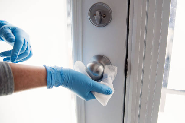 Hands with glove wiping doorknob. Female hands with blue glove wiping doorknob with disinfectant wipe. Horizontal indoors close-up with copy space. cleaning product stock pictures, royalty-free photos & images
