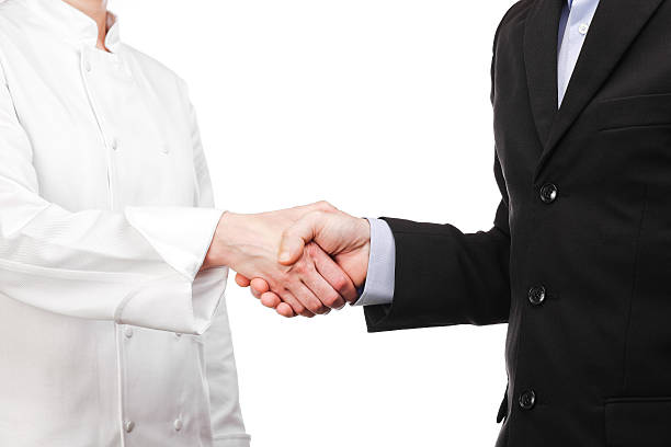handshake between a cook and a businessman stock photo