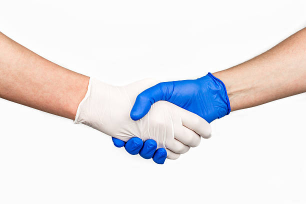 Handshake with blue and white medical gloves. stock photo