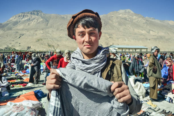 guapo joven pastún afgano sonríe sosteniendo bufanda en el mercado afgano - afghanistan fotografías e imágenes de stock
