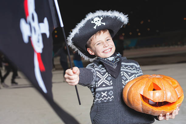Handsome boy dressed in Halloween pirate fancy dress with flag stock photo