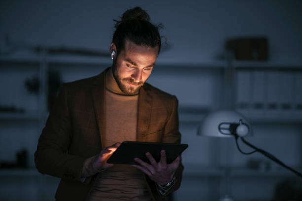 Handsome Businessman Standing in His Office Using a Digital Tablet During a Late Night at Work stock photo