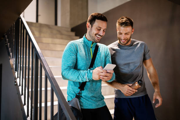 Handsome fit men friends talking, smiling after workout in gym stock photo