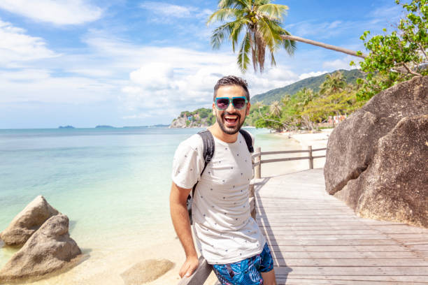 Handsome happy man wearing white T-shirt at the sea or the ocean background. Travel vacation stock photo