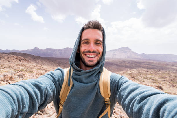 Handsome hiker taking a selfie hiking a mountain using his smartphone stock photo