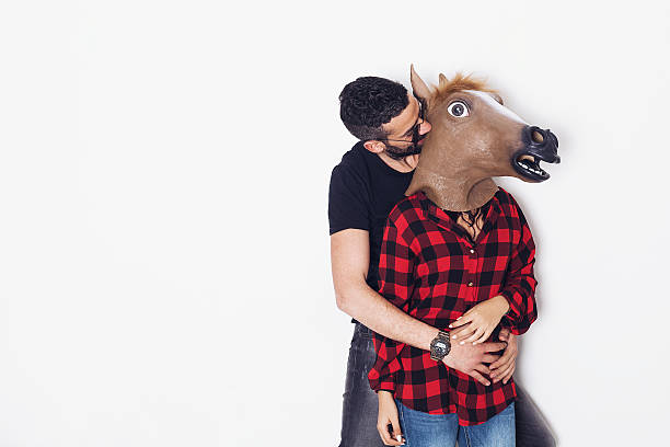 Handsome man portrait hugging his horse head girlfriend Handsome man portrait hugging his horse head girlfriend horse mask photos stock pictures, royalty-free photos & images