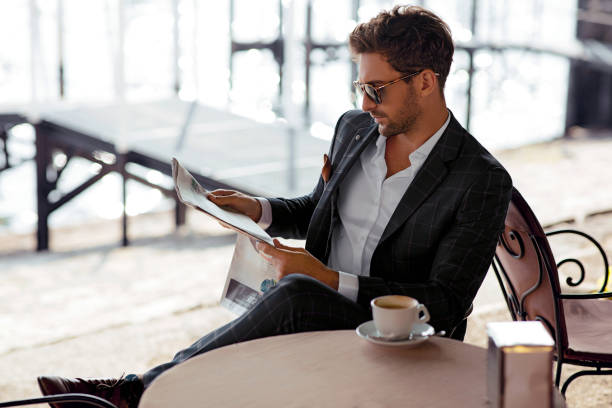 Handsome man reading newspaper in cafe stock photo