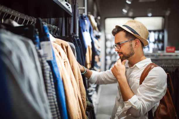 Handsome man shopping for new clothes in store Handsome young man shopping for new clothes in store mens fashion stock pictures, royalty-free photos & images