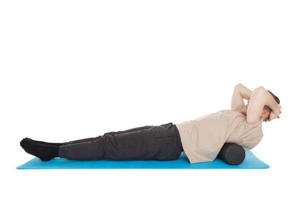 Handsome man shows exercises using a foam roller Handsome man shows exercises using a foam roller for a myofascial release massage of trigger points. Massage of the lower back muscle. Isolated on white. stretching and releasing your lower back stock pictures, royalty-free photos & images