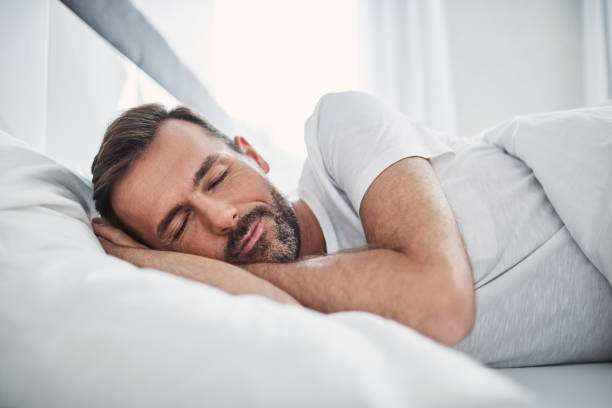 guapo hombre durmiendo en la cama - sleeping fotografías e imágenes de stock