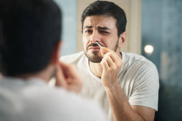 Handsome Man Trimming Nose Hair In Bathroom stock photo