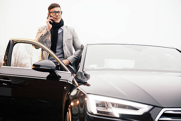 Handsome man using iPhone 6+ and driving new Audi A4 Novi Sad, Serbia - December 20, 2015: Attractive young man speaking on iPhone 6 and entering in new Audi A4 S line 2.0 tdi. New Audi model, production year 2015, came to Easter European markets at the end of the year and attracted many old and new Audi fans. This model contains full S line optional sport equipment, alloy 19" wheels and Led headlights and is priced around 50.000€.  audi photos stock pictures, royalty-free photos & images