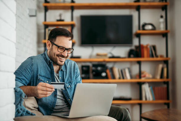 handsome man with laptop and credit card at home, portrait. - credit card imagens e fotografias de stock