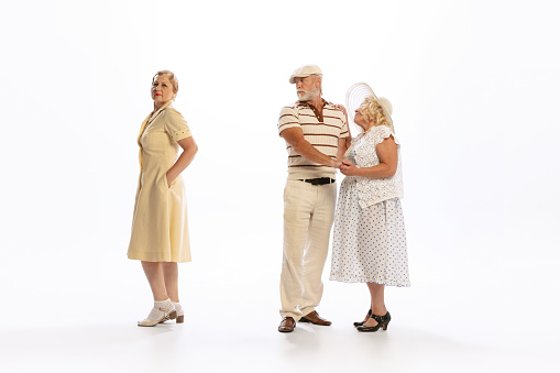 Love triangle, intrigue. Handsome senior man and two charming women in vintage retro style outfits isolated on white background. Concept of relations, family, 1960s american fashion style and art.