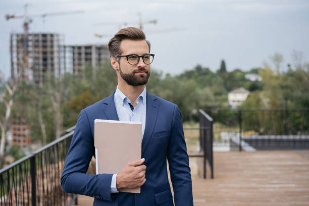 handsome stylish architect holding business documents, planning project looking on copy space - europe city map stockfoto's en -beelden