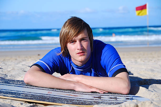 Handsome teenage, young adult male  lying on Beach  teenage boys men blond hair muscular build stock pictures, royalty-free photos & images