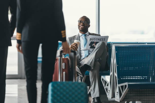 handsome young businessman looking at female pilot passing by while wait for flight at airport lobby - airport lounge imagens e fotografias de stock
