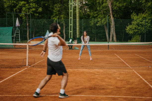 Handsome young couple playing tennis on tennis court outdoors stock photo