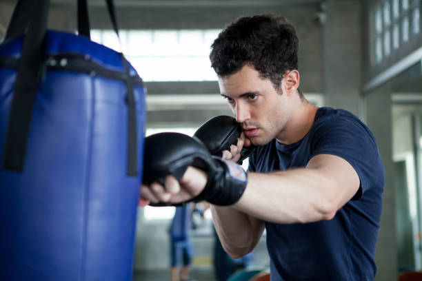 Handsome young man boxer is exercising with a punching bag at training fitness gym.male boxing workout sports stock photo