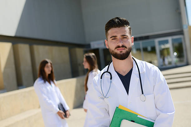 handsome young man medical student in hospital university campus portrait of a handsome young man medical student outdoor in front of hospital university campus best medical schools stock pictures, royalty-free photos & images
