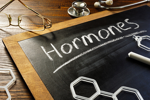 Handwritten word hormones on the blackboard and glasses.