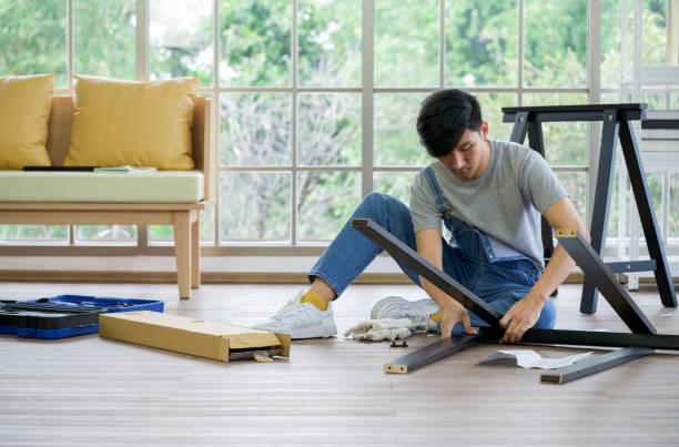 Handyman installing wooden bench in new house. House renovation service. Morning work atmosphere in the living room. stock photo